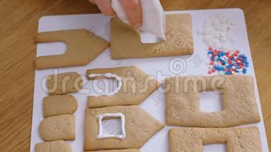 女人`手装饰着糖糖甜糖霜饼干，用于姜饼屋。 烹饪自制姜饼屋.. 顶级